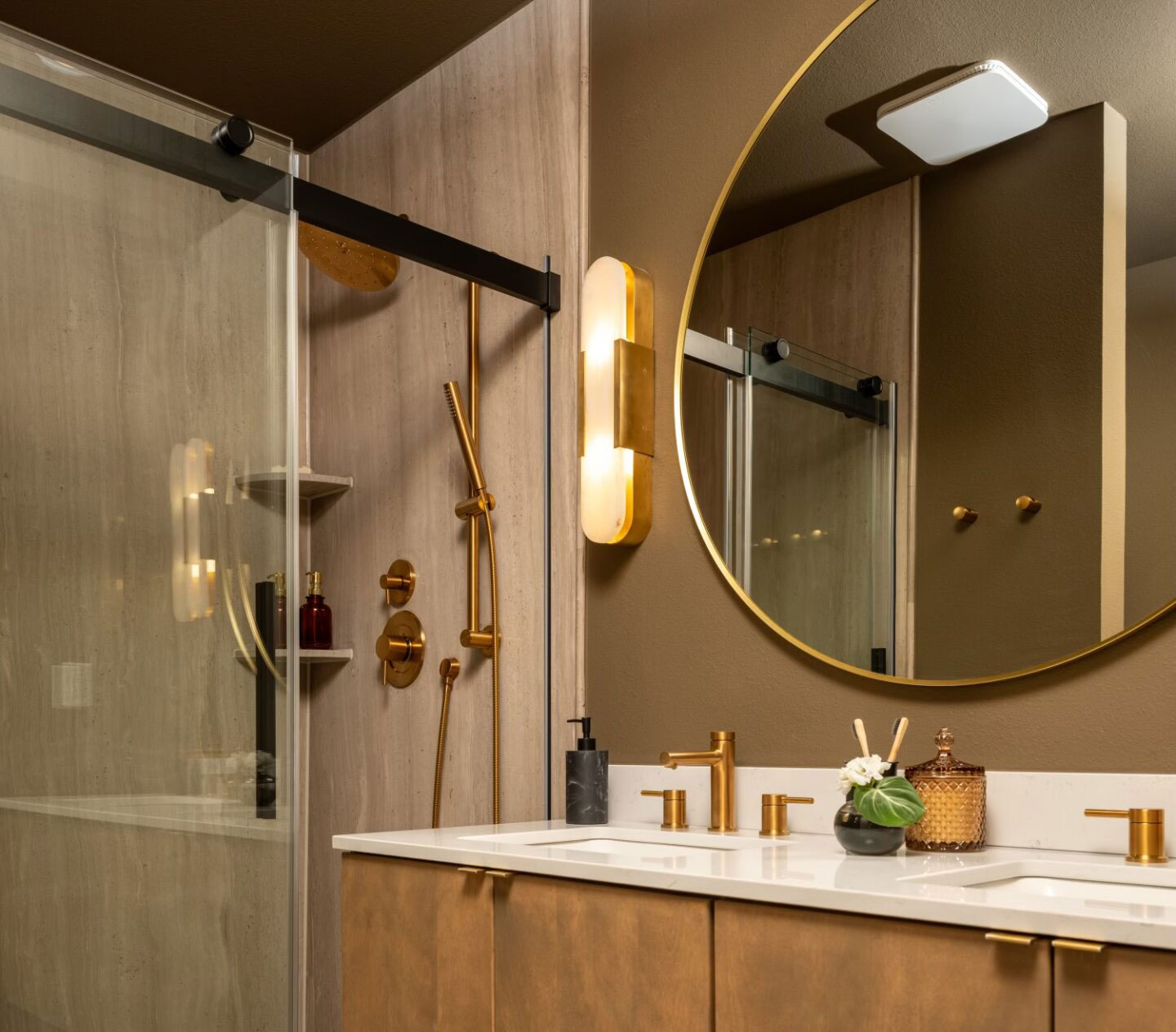 Spa-inspired bathroom featuring a warm wood vanity, stone-look shower walls, brass fixtures, and soft lighting for a calm, luxurious feel.
